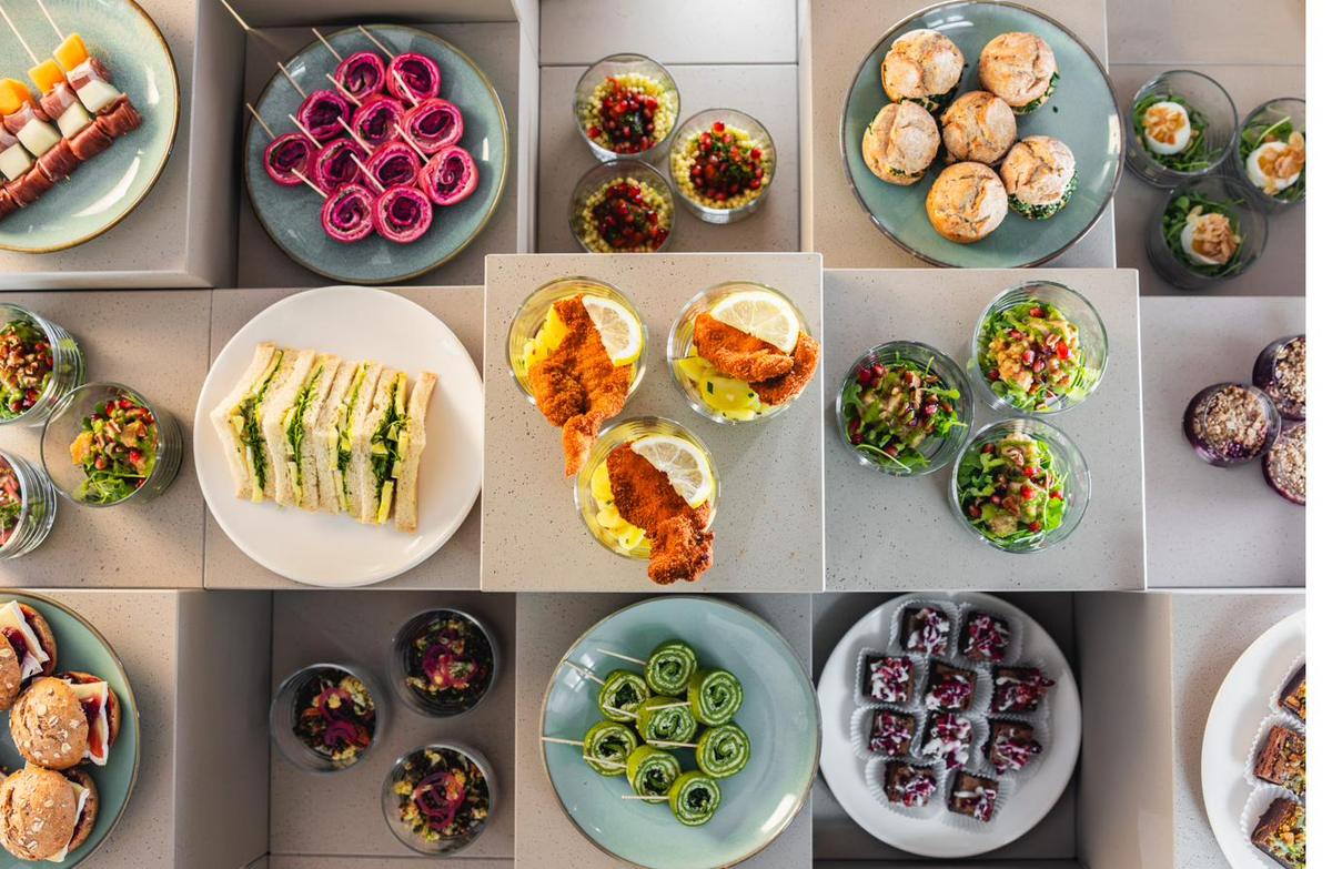 Canapés, Sandwiches und kleine Salate von oben fotografiert, angerichtet auf hellen Platten