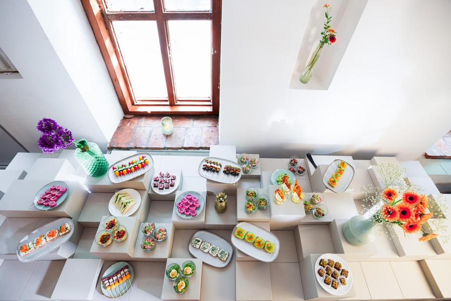 Fingerfood-Buffet mit Etageren und frischen Blumen in einem hellen Raum