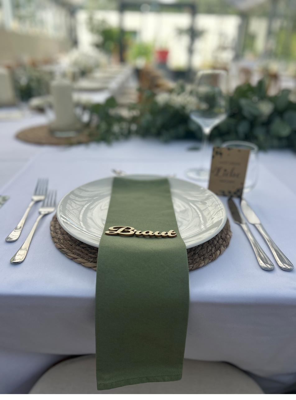 Gedeck an der Hochzeitstafel mit grüner Serviette, Platzkarte und Eukalyptus